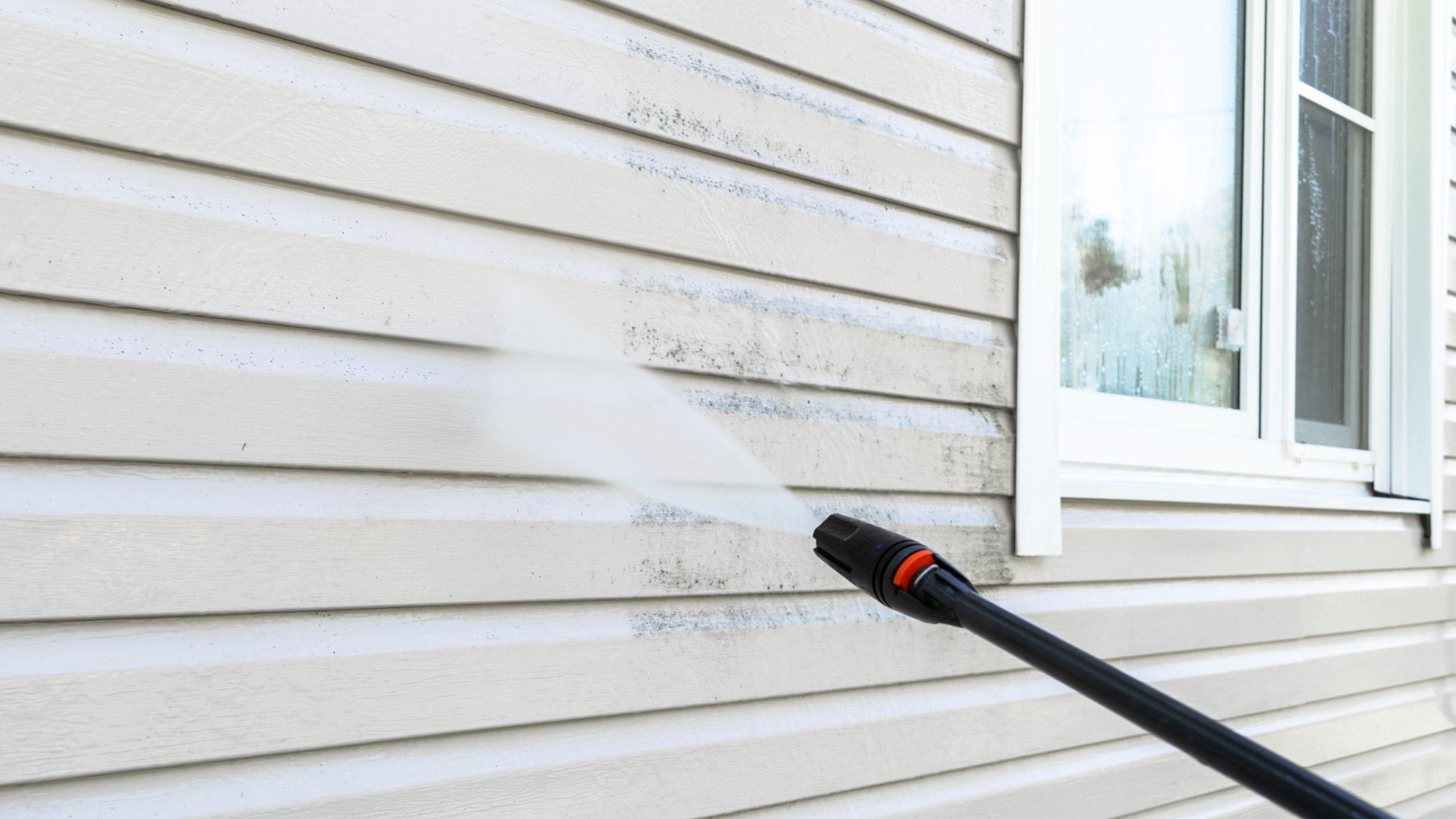 House siding undergoing soft washing pressure wash for effective cleaning