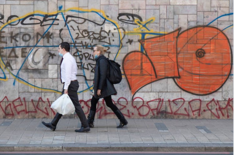 Professional graffiti removal service in action: People walking past graffiti-covered wall about to be cleaned